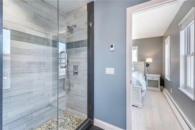 bathroom with wood-type flooring, a shower with shower door, and baseboard heating