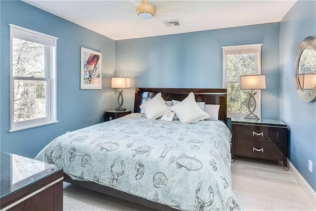 bedroom with multiple windows and light hardwood / wood-style flooring