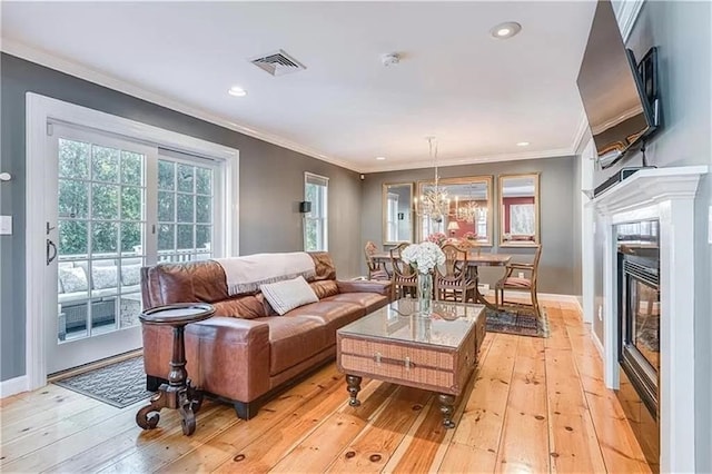 living room featuring ornamental molding, a chandelier, and light wood-type flooring