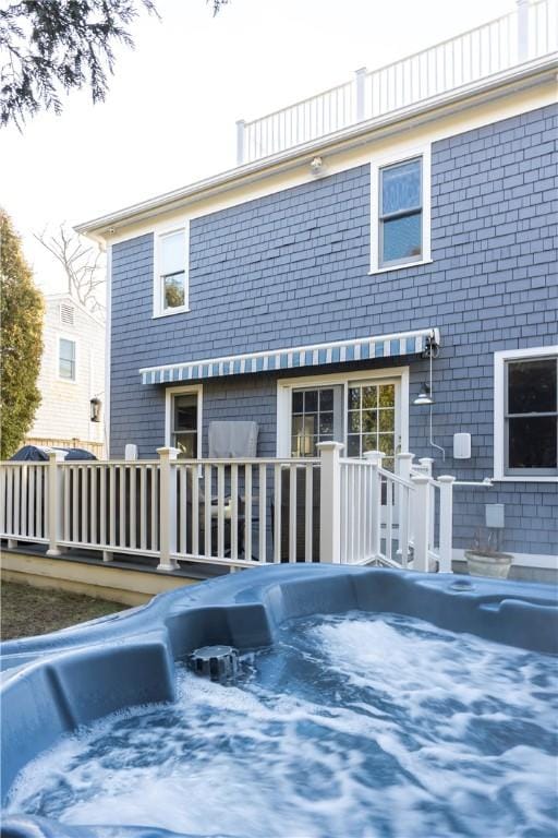 back of property featuring a wooden deck and a hot tub