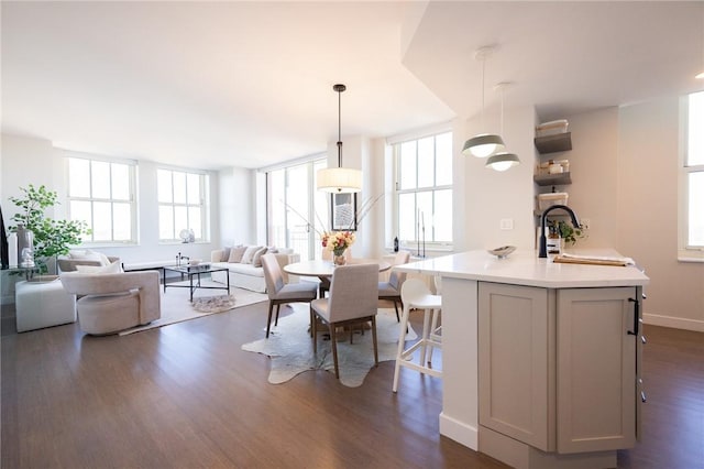 kitchen featuring sink, decorative light fixtures, dark hardwood / wood-style floors, a kitchen breakfast bar, and an island with sink