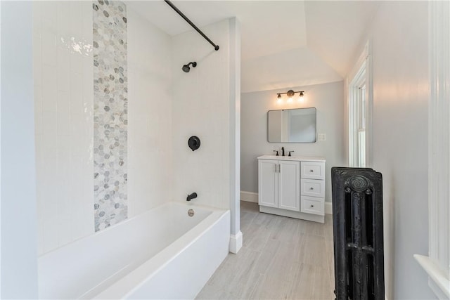 bathroom with tiled shower / bath, lofted ceiling, and vanity