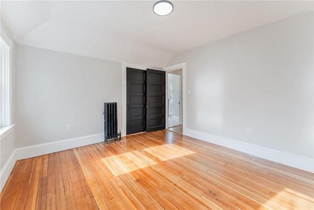 spare room featuring vaulted ceiling and light hardwood / wood-style floors