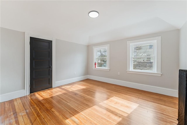 unfurnished room with hardwood / wood-style flooring and vaulted ceiling