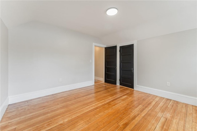 unfurnished bedroom featuring hardwood / wood-style flooring, lofted ceiling, and a closet