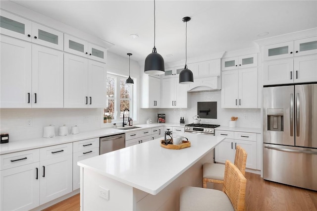 kitchen featuring sink, a breakfast bar area, stainless steel appliances, white cabinets, and a kitchen island