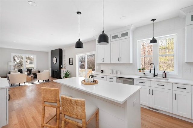 kitchen with a kitchen bar, sink, a center island, hanging light fixtures, and white cabinets