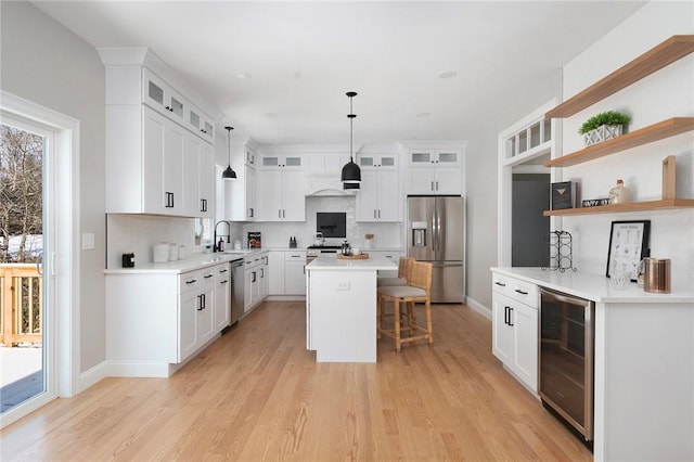 kitchen with wine cooler, sink, a center island, stainless steel appliances, and white cabinets