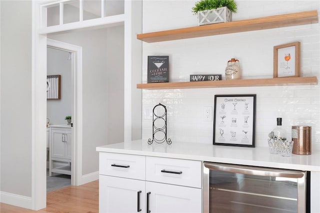 bar with wine cooler, backsplash, white cabinetry, and light hardwood / wood-style floors