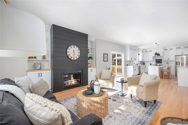 living room with light hardwood / wood-style floors and a large fireplace