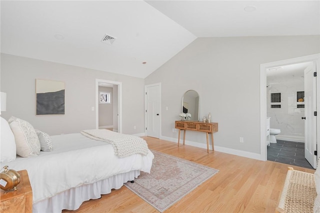 bedroom with ensuite bath, lofted ceiling, and dark hardwood / wood-style floors