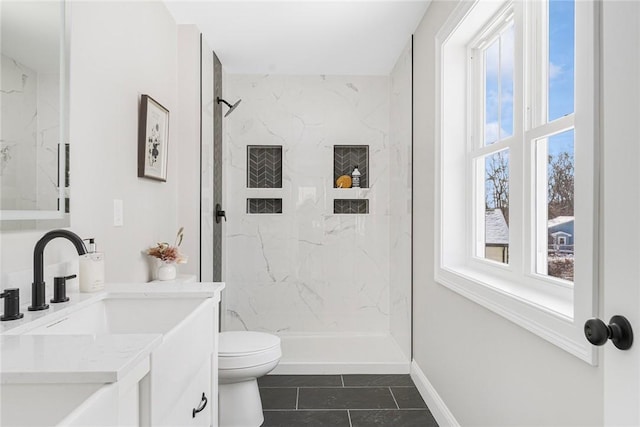 bathroom with vanity, a wealth of natural light, toilet, and a tile shower