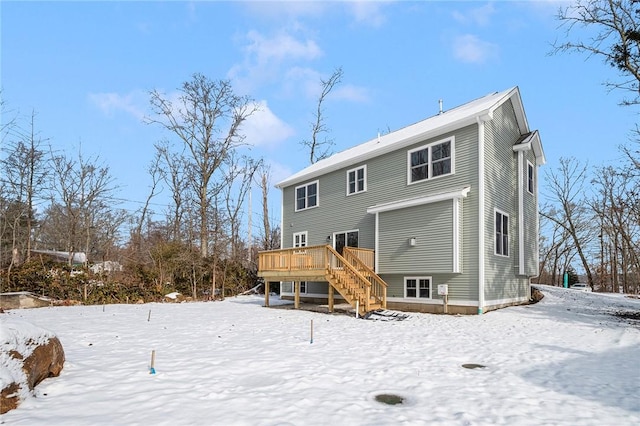 snow covered back of property with a wooden deck