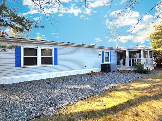 view of front of house with a front lawn, central AC, and a sunroom