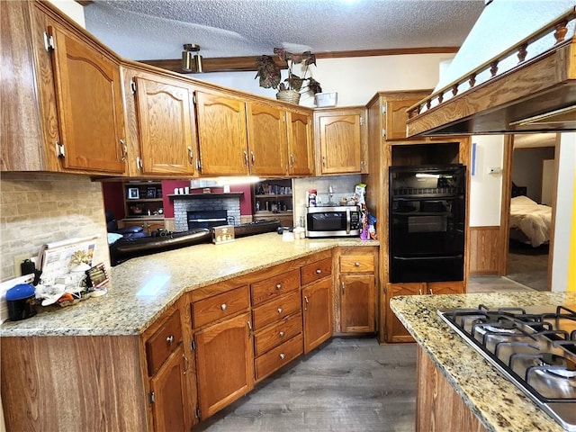 kitchen with light stone counters, tasteful backsplash, a textured ceiling, dark hardwood / wood-style floors, and stainless steel appliances