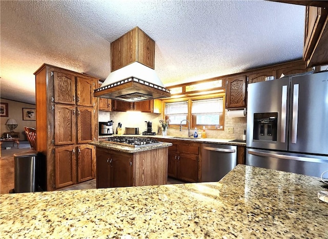 kitchen featuring premium range hood, sink, light stone counters, a kitchen island, and stainless steel appliances