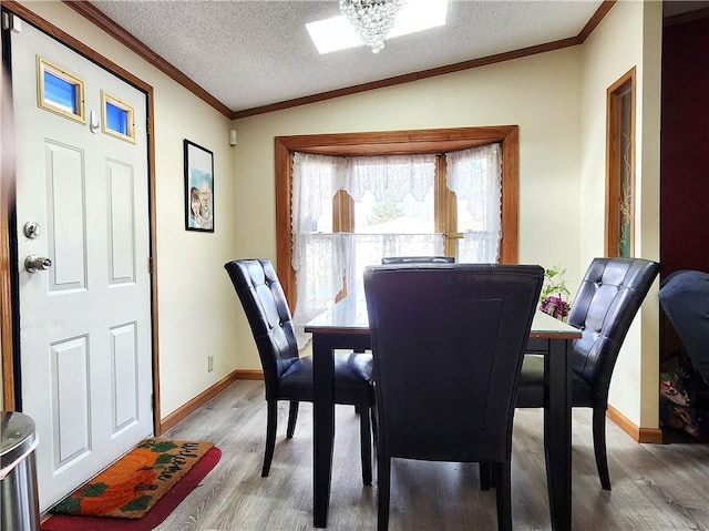 dining space featuring vaulted ceiling, ornamental molding, hardwood / wood-style floors, and a textured ceiling