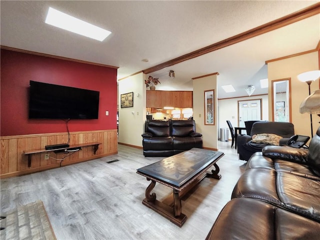 living room with ornamental molding, wooden walls, radiator heating unit, and light wood-type flooring