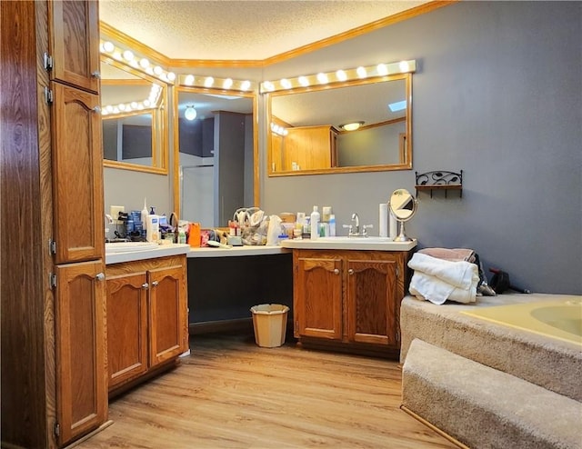 bathroom with wood-type flooring, a textured ceiling, crown molding, and vanity