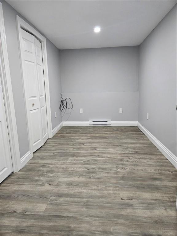 unfurnished room featuring a baseboard heating unit and light hardwood / wood-style flooring