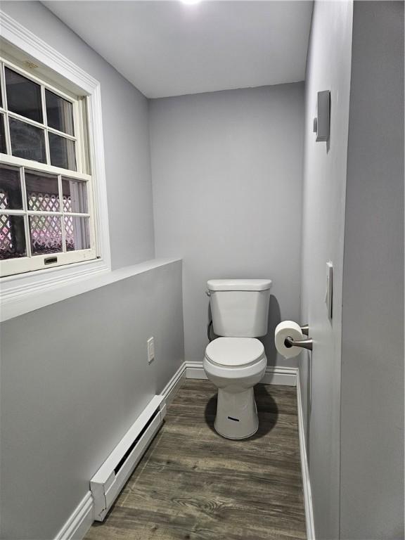 bathroom featuring hardwood / wood-style flooring, toilet, and baseboard heating