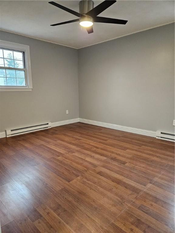 spare room with crown molding, ceiling fan, hardwood / wood-style floors, and a baseboard heating unit