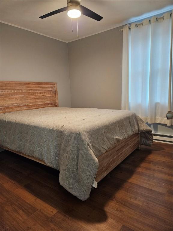 bedroom with a baseboard heating unit, crown molding, dark hardwood / wood-style floors, and ceiling fan