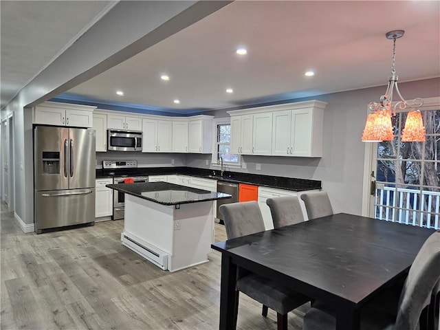 kitchen featuring pendant lighting, stainless steel appliances, a center island, and white cabinets