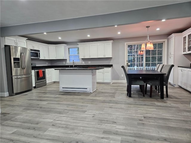 kitchen featuring a center island, hanging light fixtures, light wood-type flooring, stainless steel appliances, and white cabinets