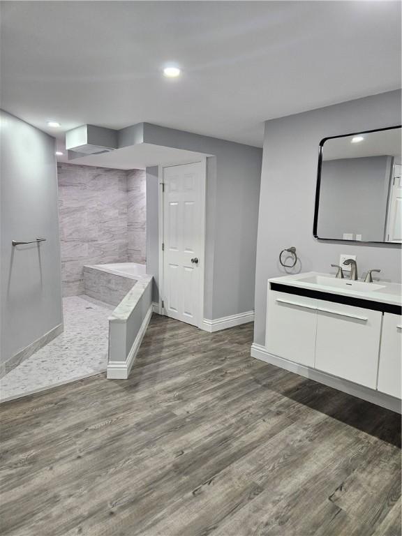 bathroom featuring wood-type flooring, vanity, and a tile shower