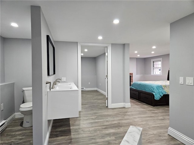 bathroom with baseboard heating, wood-type flooring, toilet, and vanity