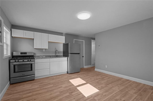 kitchen featuring light wood-type flooring, light stone countertops, white cabinets, and appliances with stainless steel finishes