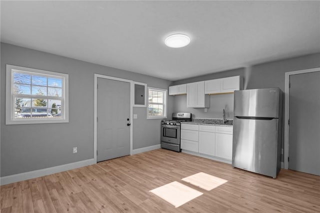 kitchen with appliances with stainless steel finishes, white cabinets, and light hardwood / wood-style floors