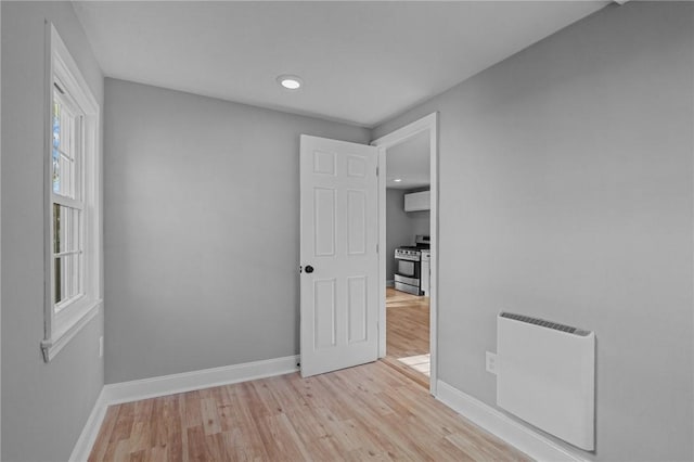 empty room with heating unit and light hardwood / wood-style flooring