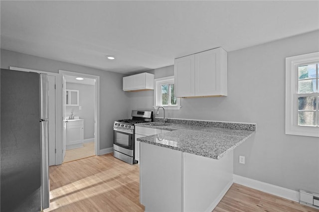 kitchen featuring sink, light hardwood / wood-style flooring, stainless steel appliances, light stone countertops, and white cabinets