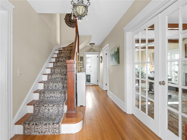 stairs featuring wood-type flooring and a chandelier