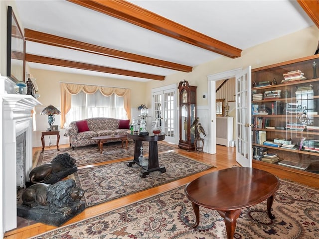 living room featuring french doors, light wood-type flooring, and beamed ceiling