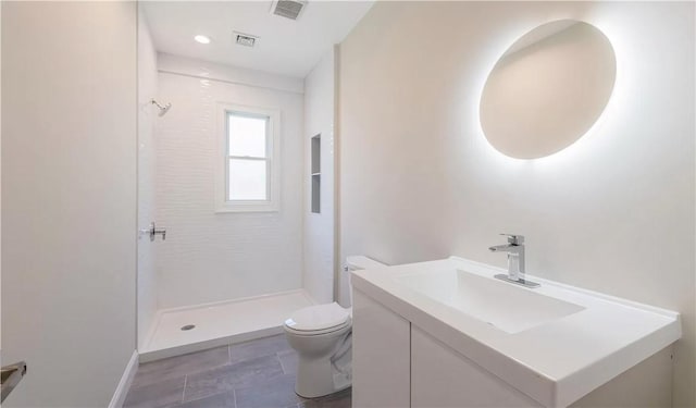 bathroom featuring vanity, toilet, and tiled shower