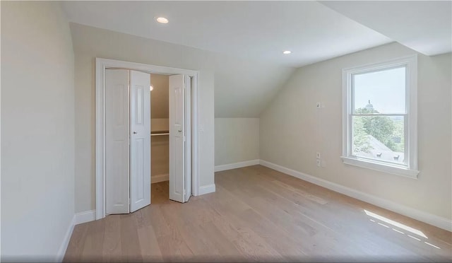 additional living space featuring vaulted ceiling and light hardwood / wood-style floors