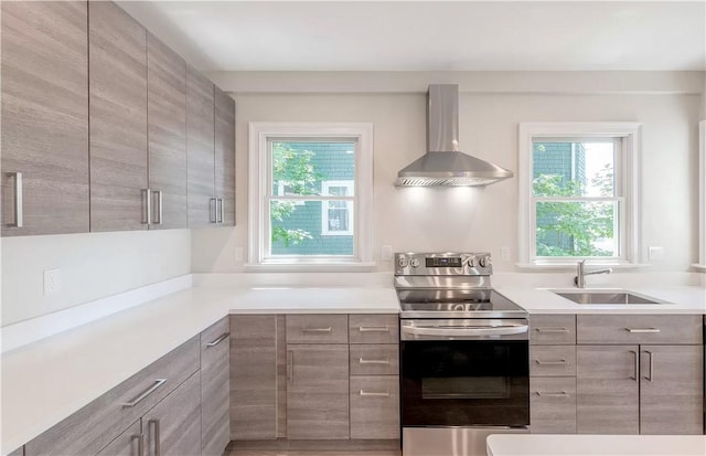 kitchen with stainless steel electric range oven, sink, and wall chimney range hood