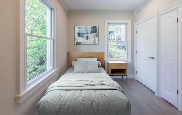 bedroom with multiple windows and hardwood / wood-style flooring