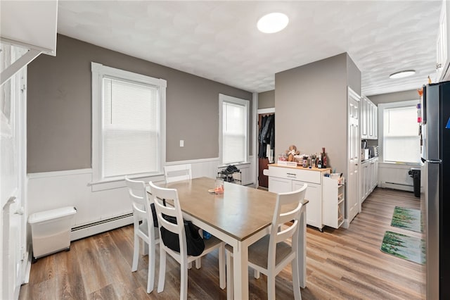 dining space featuring light wood-type flooring and baseboard heating