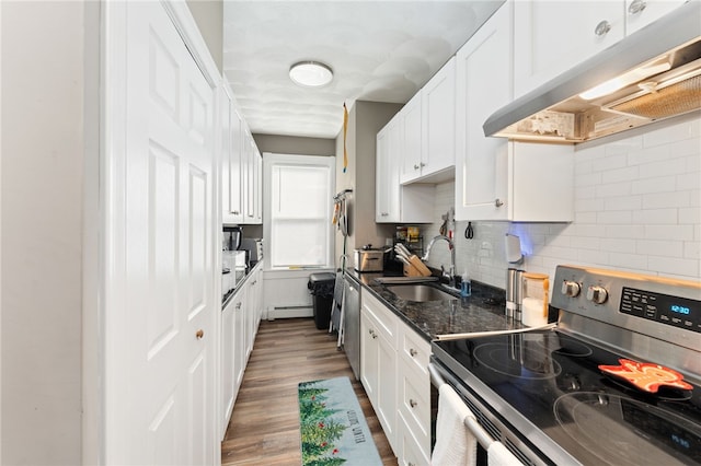 kitchen with sink, white cabinetry, stainless steel appliances, a baseboard radiator, and dark stone counters