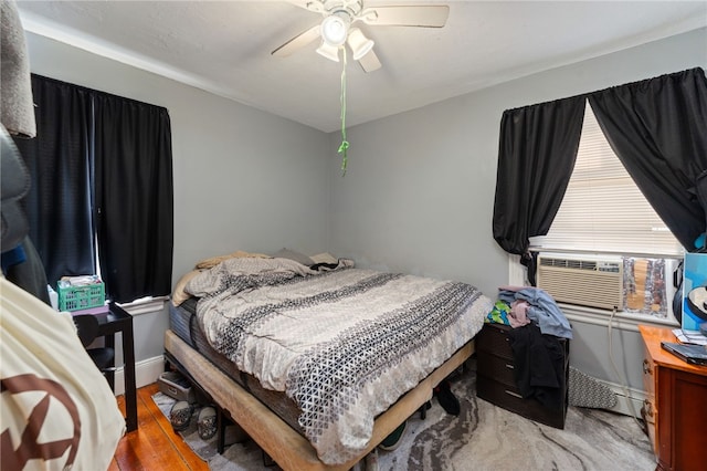 bedroom with cooling unit, light hardwood / wood-style flooring, and ceiling fan