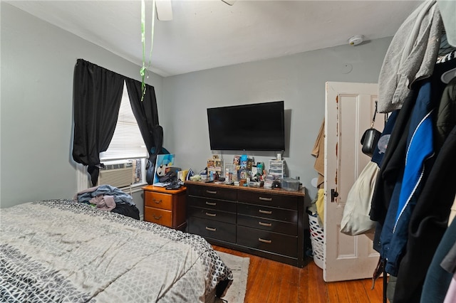 bedroom with ceiling fan, cooling unit, and dark hardwood / wood-style flooring