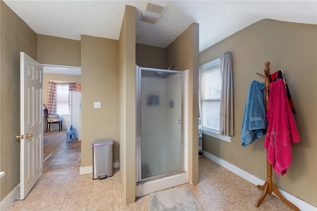 bathroom featuring a shower with door, vaulted ceiling, and plenty of natural light