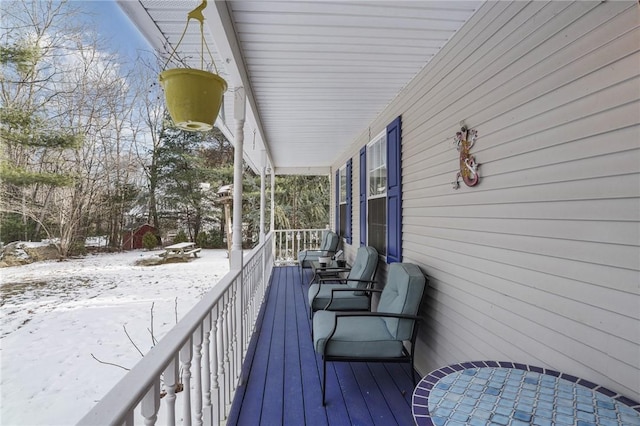 snow covered deck featuring covered porch