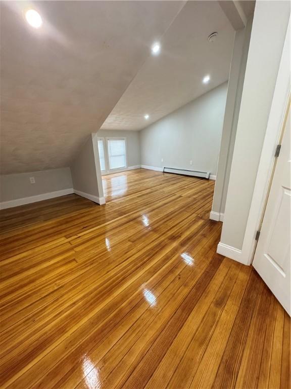 bonus room featuring baseboard heating, lofted ceiling, and light hardwood / wood-style flooring