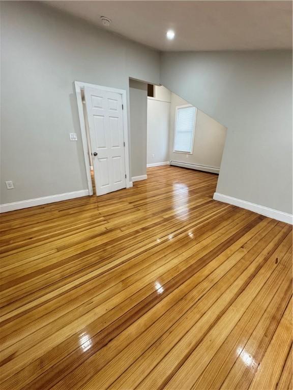 bonus room with vaulted ceiling, baseboard heating, and light hardwood / wood-style floors