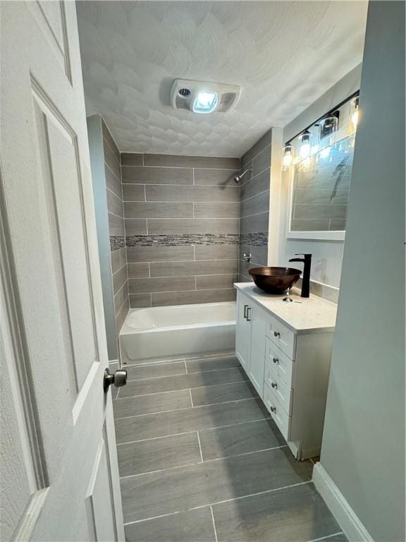 bathroom featuring vanity, tiled shower / bath combo, and a textured ceiling